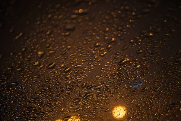 Naturlige dråber vand på glas, nat foto med en gade lys udenfor - Stock-foto