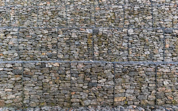 Μεταλλικά κλουβιά γεμάτα πέτρες. Gabions προστατευτικό τοίχωμα γεμάτο με πέτρες και δεμένο με χοντρό μεταλλικό σύρμα. Σχέδιο φόντου της Γκαμπόν — Φωτογραφία Αρχείου