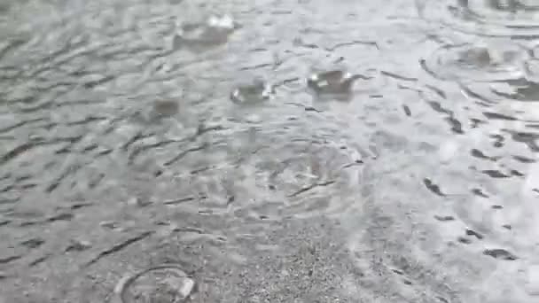 Az esőcseppek beleesnek a tócsába a szürke betonon, a nagy esőzések lelassulnak.