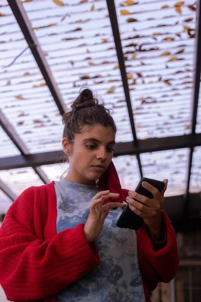 young woman with mask hanging from her ear texting