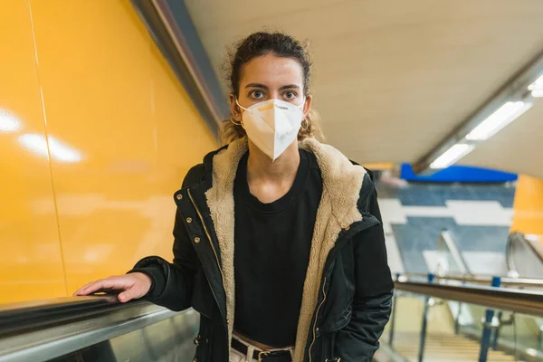 Yeni normal. Metroda yürüyen genç bir kız. Metroda yürüyen genç kız. Covid 'e karşı maske. Yüz maskeli bir genç. Salgın.