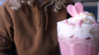 Pancar suyu ve bitki sütüyle bir bardak pembe latte içen bir kadın. Sağlıklı vejetaryen içeceği.