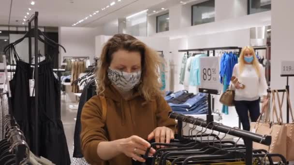 Las mujeres que usan mascarillas para comprar ropa en la tienda de ropa durante la pandemia por Coronavirus. Bialystok, Polonia, 20 de mayo de 2020. — Vídeos de Stock