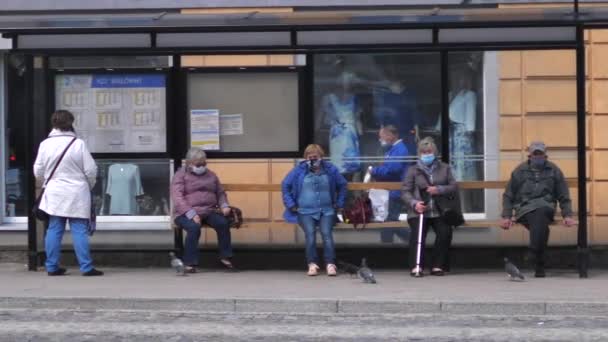 Социальная дистанция, коронавирусная пандемия. Старшие люди в медицинской маске на автобусной остановке. Белысток, Польша, 20 мая 2020 г.. — стоковое видео