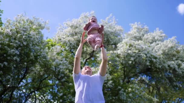 Jonge vader gooit zijn dochtertje hoog in de lucht buiten in de zomer. Happy Family Lifestyle. — Stockvideo