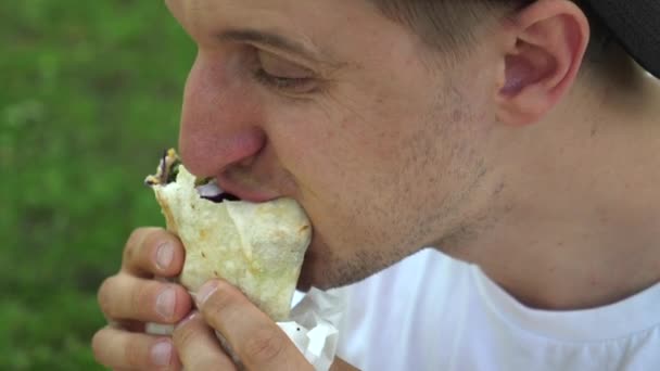 Muž jí veganský zábal a olizuje si rty. Koncept pouličního jídla. — Stock video