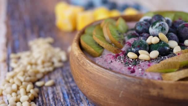 Smoothie Bowl With Fresh And Frozen Blueberries, Kiwi, Banana, Dragonfruit Powder And Pine Nuts. — Stok Video