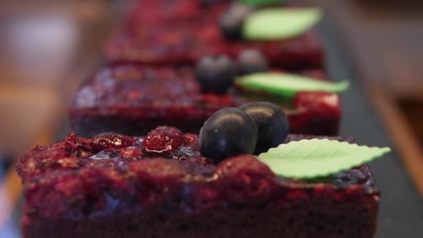 Linia czerwonych aksamitnych ciastek z jagodami ozdobionych jagodami i pozostawić w cukierni — Wideo stockowe