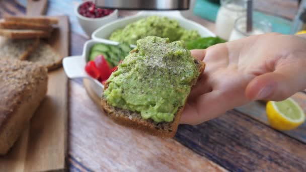 Salar una tostada de aguacate en una mano para un desayuno saludable. — Vídeos de Stock