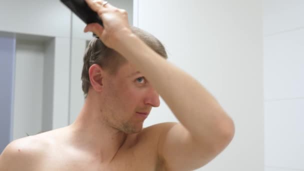 Młody człowiek obcinający własne włosy podczas epidemii koronawirusa. Fryzura kwarantannowa. — Wideo stockowe