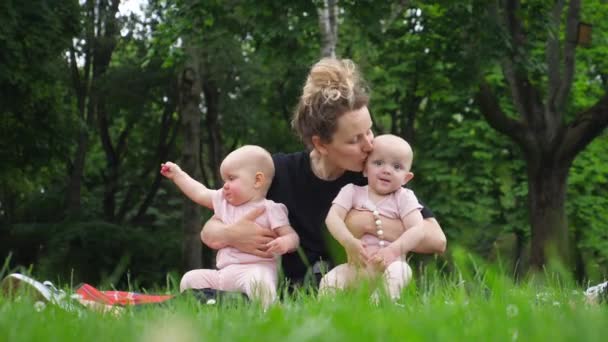 Madre besando a sus bebés gemelos divertirse al aire libre en el parque. — Vídeos de Stock