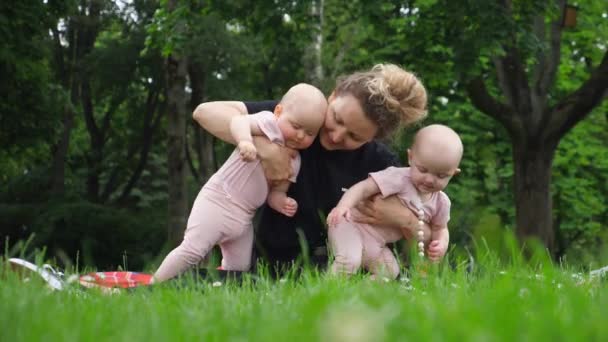 Szczęśliwa koncepcja rodziny. Młoda matka gospodarstwa Twin dzieci w parku. — Wideo stockowe