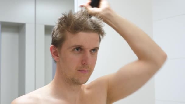 Młody człowiek obcinający własne włosy za pomocą przycinacza podczas kwarantanny koronawirusowej — Wideo stockowe