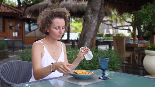 Mujer caucásica se quita la mascarilla para comer pasta en un restaurante al aire libre — Vídeos de Stock