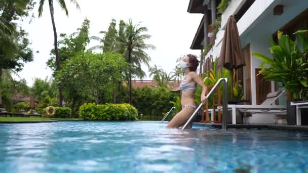 Mulher branca jovem com uma máscara facial mergulhando na piscina privada em sua villa — Vídeo de Stock