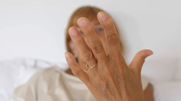 Orta yaşlı kadın bileklerini ve parmaklarını kontrol ediyor. Hazırda bekle.