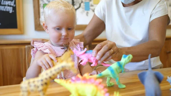 Linda niña caucásica jugando con dinosaurios dentro — Foto de Stock