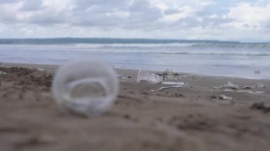 Plajda bırakılan plastik bardağı kapat. Arkaplanda çok daha fazlası var. 