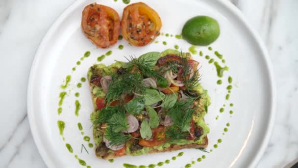 Horní pohled na toast na rostlinné bázi s avokádem smash topped se spoustou zeleniny — Stock video