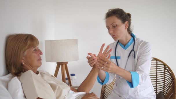 Mujer trabajadora de la salud que realiza una prueba de diagnóstico en la mano de los pacientes para verificar la artritis. — Vídeos de Stock