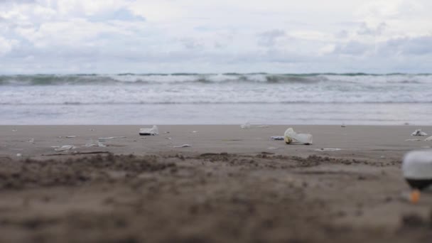 Близько сміття залишилося на пляжі. Пластикова чашка з залишком напою в ній — стокове відео