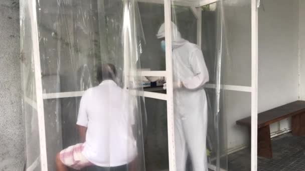 Homem em cubículo especial sendo testado para o vírus da corona por especialista em saúde em um traje de proteção. — Vídeo de Stock