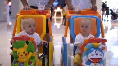İki sevimli beyaz bebek çocuk arabasında süpermarkette. 
