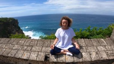 Uçurumun tepesinde meditasyon yapan sarışın bir kızın geniş açılı görüntüsü. Gezegenle birlik 