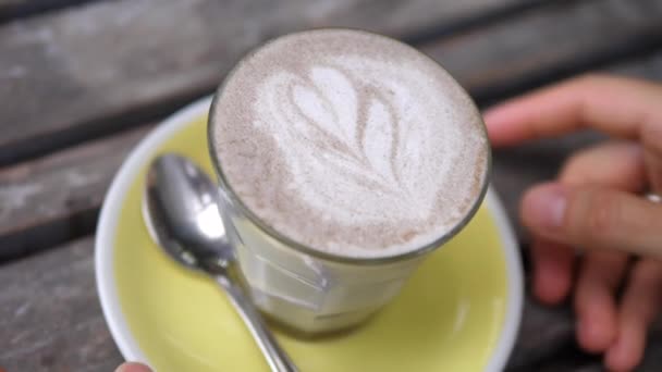 Hands taking away a glass of dairy free cappuccino with hearty art foam. — Stock Video