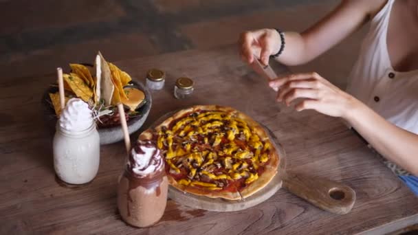 Vue de dessus des mains prenant des photos du déjeuner végétalien se composait de pizza, nachos et milkshakes dans un bocal en verre servi sur une table en bois. Concept de blogging alimentaire — Video