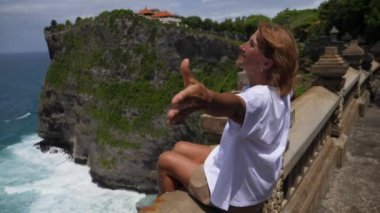 Doğayı seviyorum. Orta yaşlı, beyaz bir kadın, kollarını açmış, gözlem masasında oturmuş okyanus manzarasını kucaklıyor.