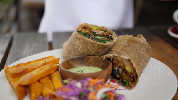 Gesundes, leckeres veganes Mittagessen mit Wrap-Sandwich, serviert mit Kartoffelfrites und Krautsalat. Veganes Streetfood-Konzept — Stockvideo