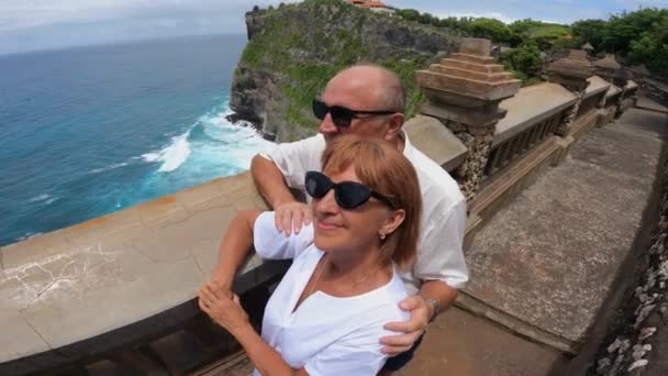 Kaukasisches Paar mittleren Alters genießt den atemberaubenden Blick auf das Meer von der Klippe — Stockvideo