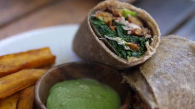 Yanında sos, lahana salatası ve tatlı patatesle servis edilen vejetaryen dürüm yakın çekim. Sağlıklı vejetaryen yaşam tarzı kavramı