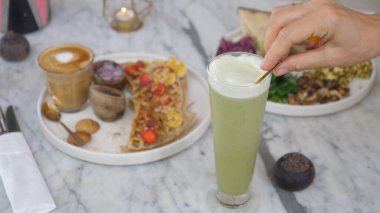 Temiz yeme konsepti. Vejetaryen waffle, omlet, sebze, bitki bazlı latte ve matcha buzlu latte.