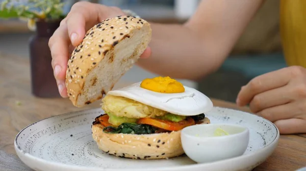 Persoon legt glutenvrij broodje bovenop een plantaardige hamburger. Straat eten in veganistische stijl — Stockfoto