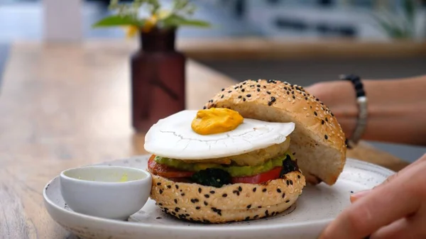 Hand serving vegan burger with plant based egg on top. Healthy vegan fast food alternatives