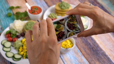 Hands taking a picture of healthy organic vegan breakfast with white smartphone. 2020-Warsaw-Poland