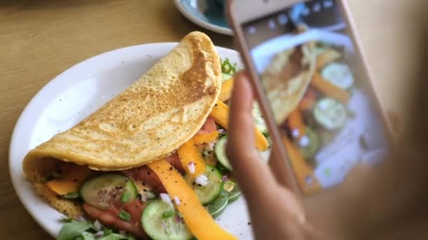 Ręce robiące zdjęcie zdrowego organicznego śniadania serwowanego na białym talerzu. Omelette z warzywami. — Wideo stockowe