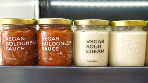 Verscheidenheid van veganistische dips in potten gepresenteerd op een display in biologische winkel. spreads op basis van planten — Stockvideo