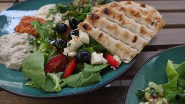 Horní pohled na dva talíře s meze, saláty a pita. Zdravá organická středovýchodní kuchyně. — Stock video