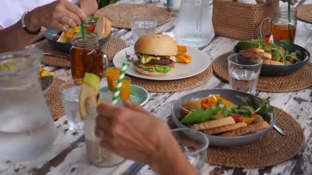 Vegansk grupplunch. Människor som dricker iste från glasburkar och äter hälsosamma växtbaserade måltider — Stockvideo