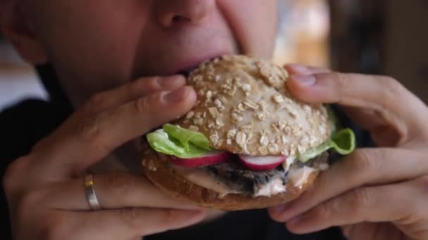 Ο άνθρωπος τρώει νόστιμα βιολογικά vegan burger. Κλείσε το στόμα σου. Υγιής έννοια του τρόπου ζωής. — Αρχείο Βίντεο