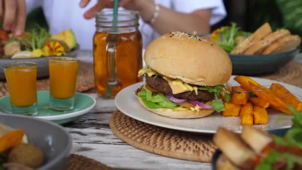 Dolly tourné sur divers repas végétaliens sains à la table- salades, hamburgers, collations et boissons. Concept de manger propre — Video