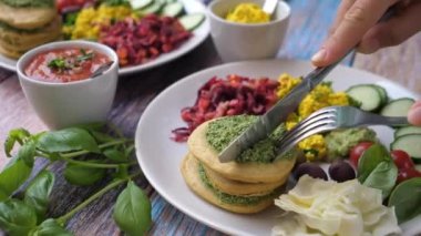 Eller krep yığınını keser. Sağlıklı organik vegan kahvaltısı beyaz tabakta servis edilir. Sağlıklı yaşam tarzı kavramı.