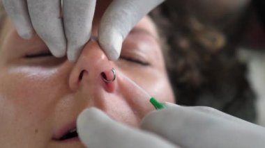 Tek kullanımlık eldivenli profesyonel piercing burun deliğine yüzük takıyor. 