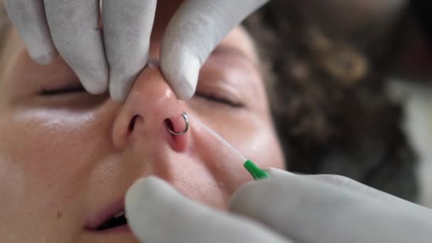 Professzionális piercer az eldobható kesztyűben, gyűrűt téve az orrlyukba. — Stock videók