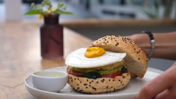 Hambúrguer vegan mão servindo com ovo à base de plantas no topo. Alternativas saudáveis vegan fast food — Vídeo de Stock