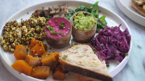 Primer plano del plato con varios entrantes veganos saludables: ensaladas, diferenciales, batatas y un brindis — Vídeos de Stock