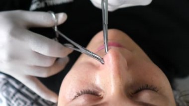 Vücut delme işlemi. Tek kullanımlık eldivenli profesyonel piercing burun halkası takıyor. 